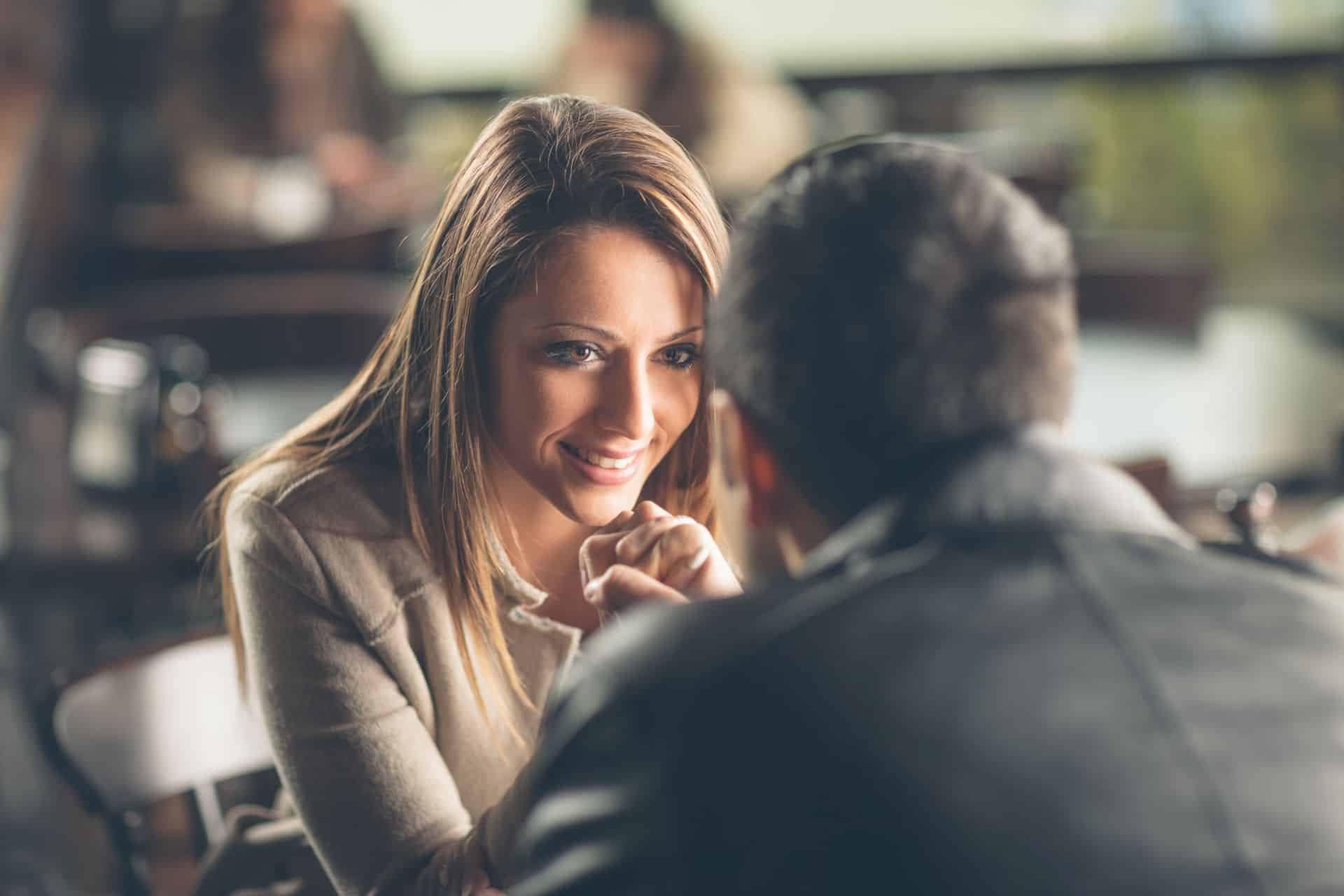 Frau hält die Hand ihres Partners beim Date und schaut ihm tief in die Augen mit einem verliebten Lächeln